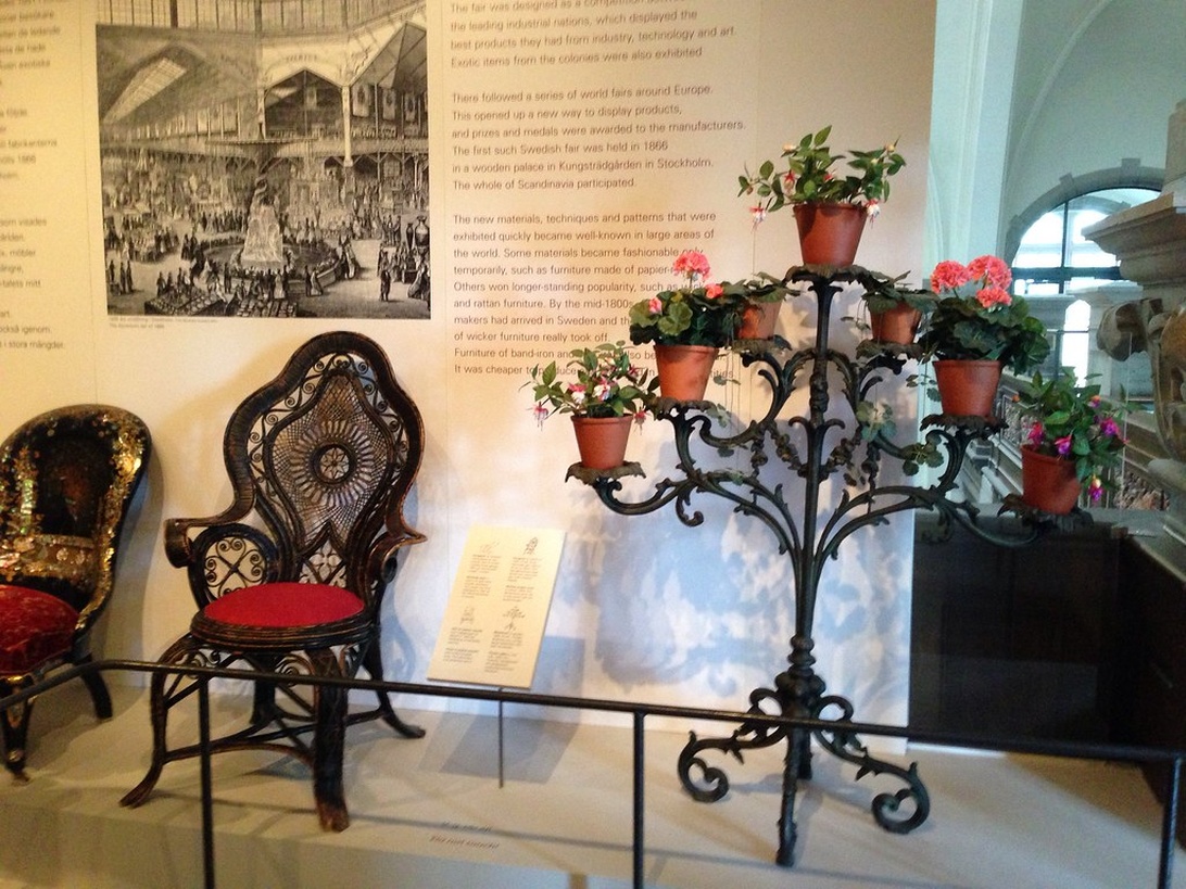 En museiutställning med historiska svenska möbler, inklusive en utsmyckad korgstol, som visar den långa traditionen av svensk designexport.